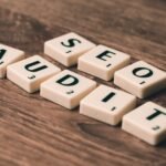 Scrabble tiles spelling SEO Audit on wooden surface, symbolizing digital marketing strategies.